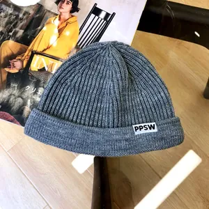 Close-up of grey knitted beanie with PPSW letter tag for kids and toddlers
