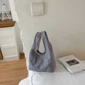 Detailansicht einer grauen, karierten Stoffhandtasche mit rotem Herzfutter im schlichten Design.