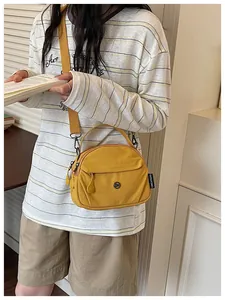Vista detallada de un bolso bandolera de tela amarillo de moda llevado por una modelo en reposo