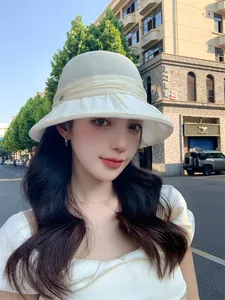 Elegant white breathable sun hat with ruffled brim shown on a model in urban setting.