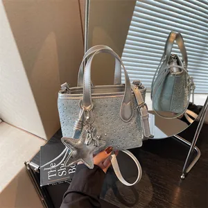 Detail view of light blue denim mini tote bag with silver rhinestones and star charm.