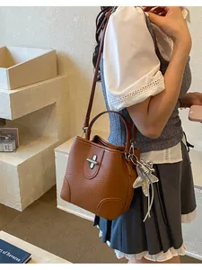 Détail de style du sac seau marron rétro avec breloque étoile et fermoir argenté