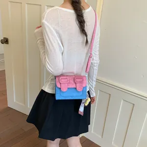 Rear view detail of a blue and pink color-blocked square crossbody bag worn by a model