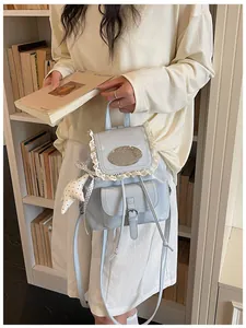 Detail of a light blue glossy backpack with lace trim and star charm in a library