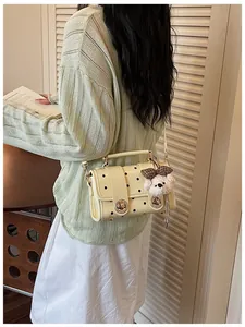 Detail view of cream vintage polka dot crossbody bag featuring a cute plush dog charm decoration