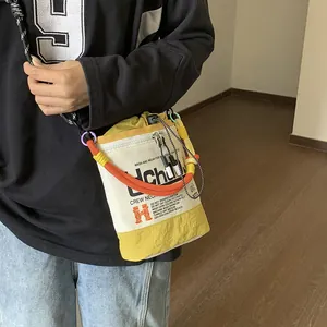 Nahaufnahme einer stylischen gelb-weißen Beuteltasche mit Seilriemen und Uchu-Druckmotiv