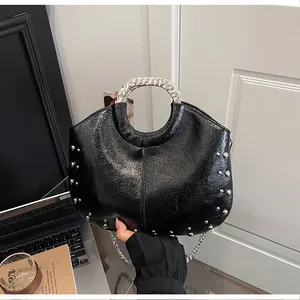 Detailed view showing the glossy black leather texture and silver studs on this handbag