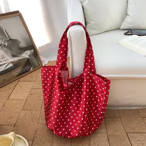 Κόκκινη τσάντα tote με λευκά πουά σε μια ζεστή ατμόσφαιρα σπιτιού δίπλα στον καναπέ.