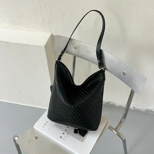 Gedetailleerd overzicht van zwarte geweven hobo bucket bag met ingewikkeld visgraatpatroon