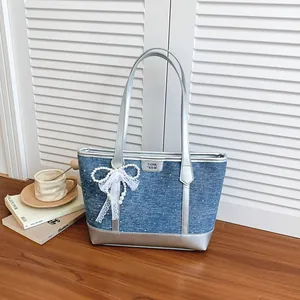 Sac cabas en jean bleu élégant avec garniture argentée et nœud en perles sur fond bois