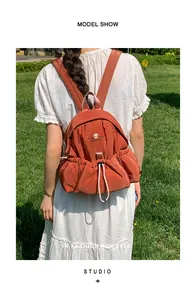 Primer plano de una elegante mochila de nailon naranja para mujer usada en un parque soleado