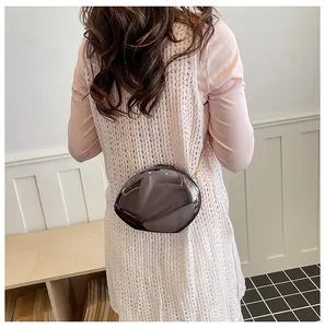 Dettaglio di una pochette a specchio a forma di conchiglia con tracolla dorata.