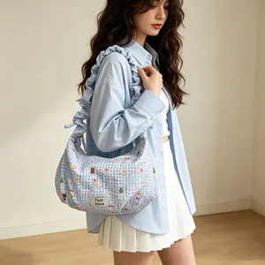 Stylish light blue gingham hobo bag with ruffle strap carried by model for casual look
