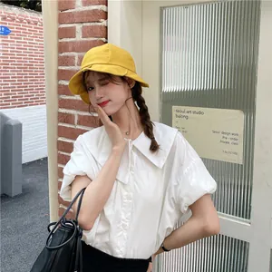 Close-up of a stylish yellow wide-brim bucket hat on a model for sun protection.