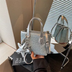Close-up detail of denim mini bucket bag with silver studs and metallic star charm