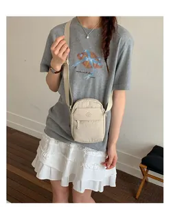 Minimalist beige nylon crossbody phone bag shown on a model for casual daily wear