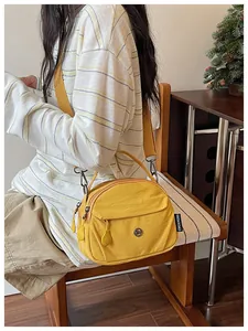 Elegante bolso bandolera de nailon amarillo usado por una modelo en un acogedor interior