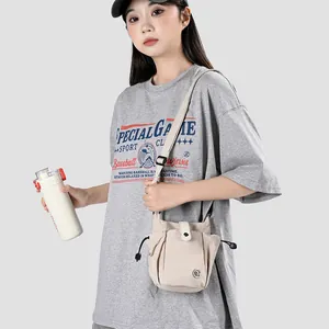 Modèle portant un mini sac bandoulière beige avec cordon de serrage et fermeture à pression
