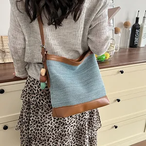 Stylish light blue woven bucket bag with brown leather trim shown in a lifestyle setting
