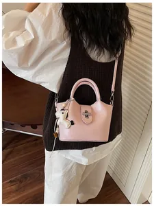 Vue détaillée d'un sac à main seau rose avec un joli charm cheval et une bandoulière.