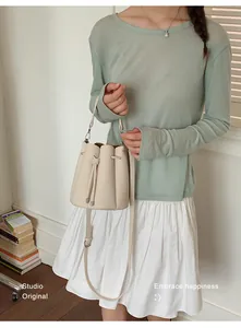 Close-up of minimalist cream bucket bag with adjustable strap worn by model