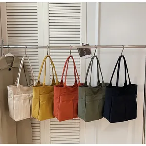Dettaglio che mostra vari colori di borse tote in tela minimaliste su un appendino