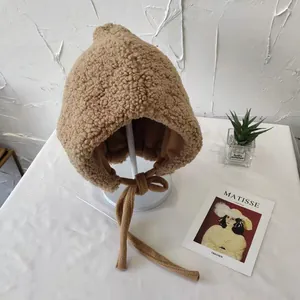 Detailed view of soft camel sherpa earflap hat with tie-up straps on a white stand