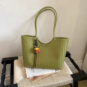 Primer plano de la textura de cuero trenzado verde y colgante decorativo en un bolso