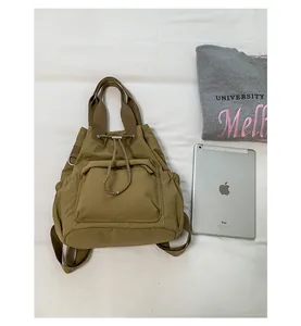 Mochila grande de color caqui con cordón junto a una tableta y sudadera sobre tela blanca