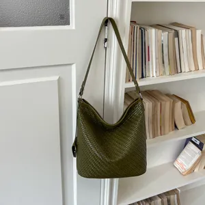 Close-up van donker olijfgroene geweven emmerzak hangend aan een witte deur in huis