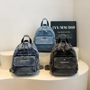 Drei modische kleine Denim-Rucksäcke in verschiedenen Waschungen auf weißem Ständer
