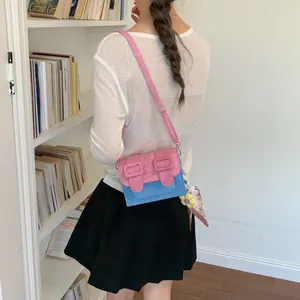 Elegant pink and blue color-block small square bag worn crossbody style by a model
