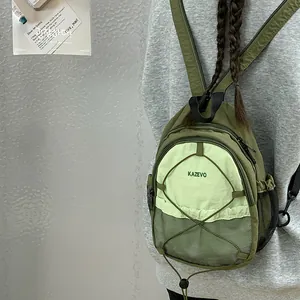 Detalle de mini mochila verde oliva con cordón cruzado y bolsillo lateral de malla