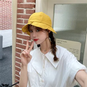 Close-up of a stylish yellow bucket hat with ruffled brim worn by an Asian model
