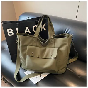 Close-up of large olive green canvas tote bag on a modern black leather sofa