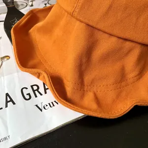 Primer plano detallado que muestra la textura del algodón naranja y las costuras del sombrero