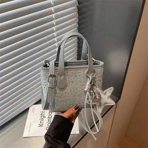 Close-up detail of a light blue denim-style handbag with silver studs and star shaped charm