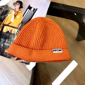 Close-up of vibrant orange ribbed knit kids' beanie featuring a PPSW decorative patch