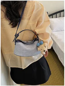 Stylish grey hobo bucket bag with a cute bear charm shown worn on shoulder