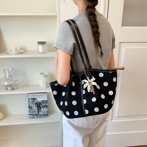 A stylish black polka dot tote bag with a palm tree charm shown on model back view
