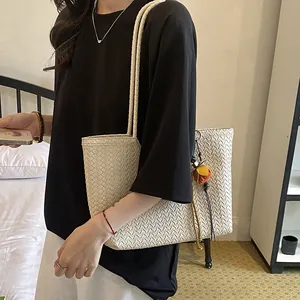 Detalle de un bolso tote tejido minimalista de gran capacidad con un colgante de borla floral