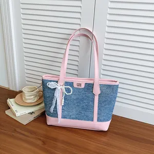 Détail d'un grand sac cabas en denim avec garniture rose et nœud en dentelle blanche