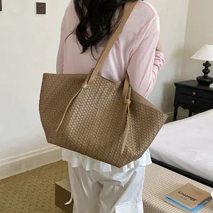 Close-up detail of a minimalist brown woven tote bag carried over the shoulder