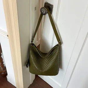 Vintage groene geweven bucket bag met grote capaciteit hangend aan een deurknop
