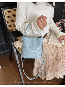 Detail shot of light blue woven bucket bag with bear charm in an elegant vintage style