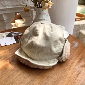Detail view of a beige winter trapper hat featuring soft pink plush fleece earflaps