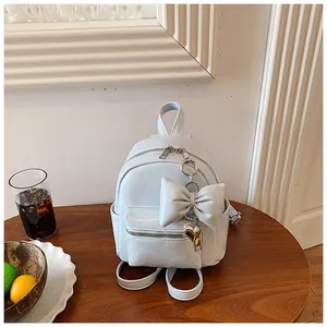Detailaufnahme eines hellblauen Mini-Rucksacks mit dekorativer Schleife und Herzanhänger.