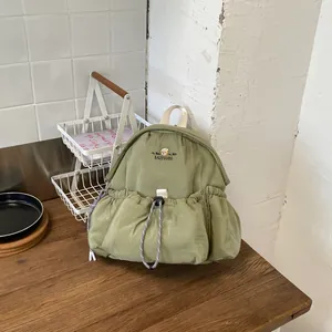 Vista lifestyle de una mochila de pana verde con práctico bolsillo de cordón frontal