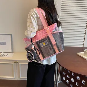 Back view of a large pink and black mesh tote bag carried by a woman for commuting