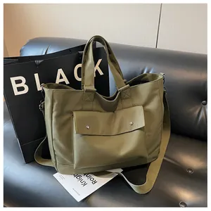 Stylish olive green large capacity tote bag shown on a black leather sofa backdrop